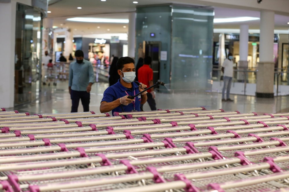 A worker, wearing a face mask, sterilizes shopping carts at a supermarket, following the outbreak of the coronavirus disease (COVID-19) in Riyadh, Saudi Arabia June 14, 2020. REUTERS/Ahmed Yosri