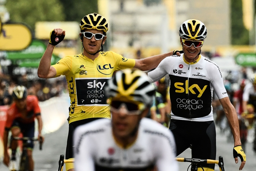 In this file photograph taken on July 29, 2018, Tour de France winner Great Britain's Geraint Thomas (L) wearing the overall leader's yellow jersey and classification third-placed Great Britain's Christopher Froome (C) react as they cross the fisnish line