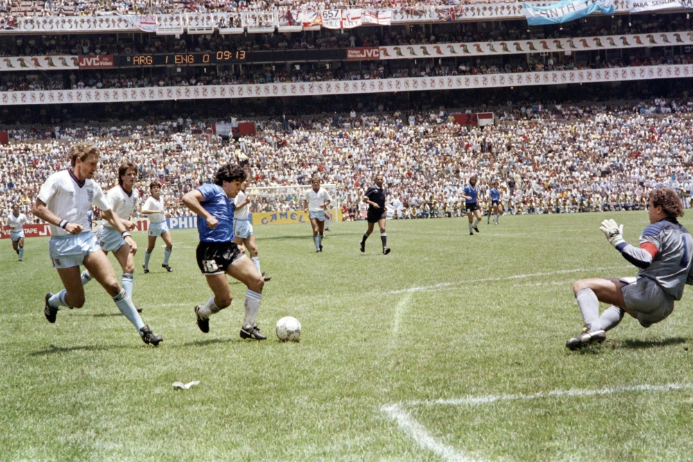 Maradona runs past English defender Terry Butcher (L) on his way to dribbling goalkeeper Peter Shilton (R) and scoring his second goal, or goal of the century, during the World Cup quarterfinal soccer match between Argentina and England in 1986 in Mexico 