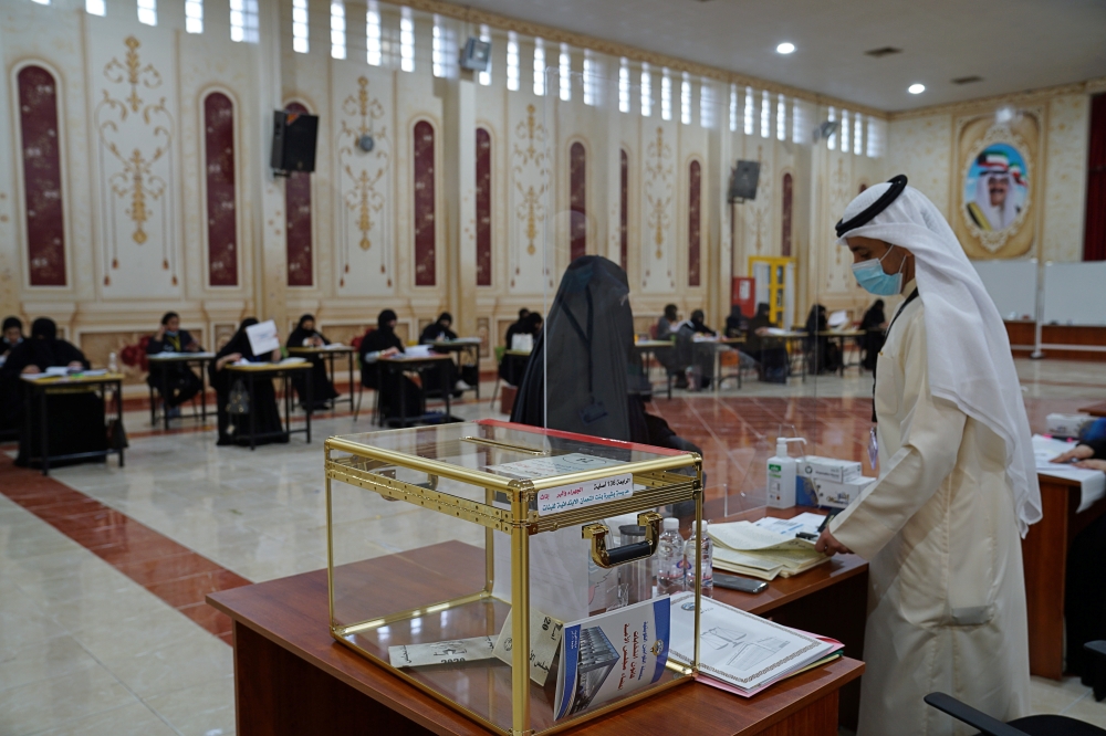 A Kuwaiti Judge checks the nationality card before a woman takes her ballot to vote during parliamentary elections at a polling station in Jahra City, Kuwait December 5, 2020. REUTERS/Stephanie McGehee