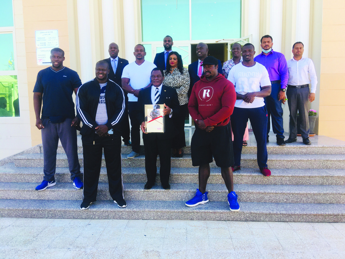 Kenya’s Ambassador to Qatar, H E Paddy C Ahenda, poses with the QSM trophy alongside strongest man athletes and embassy staff.