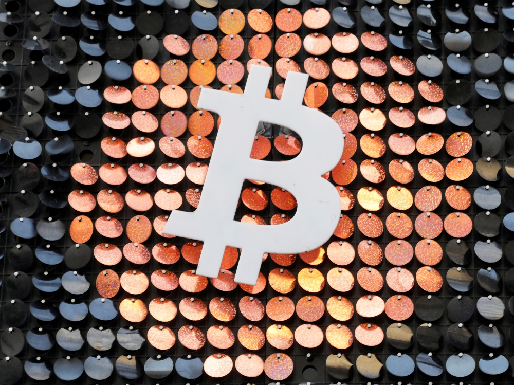 FILE PHOTO: FILE PHOTO: The logo of the Bitcoin digital currency is seen in a shop in Marseille, France, February 7, 2021. REUTERS/Eric Gaillard