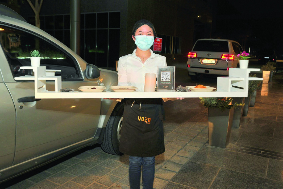 A waiter serves customers in their cars outside a restaurant in North Gate Mall. Pic: Abdul Basit/The Peninsula