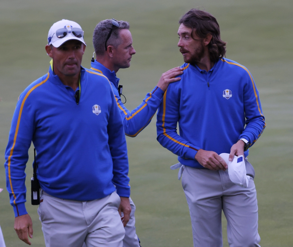 Team Europe's Tommy Fleetwood with Team Europe captain Padraig Harrington and Team Europe vice captain Luke Donald on the 18th green after halving the match during the Four-balls Reuters/Mike Segar