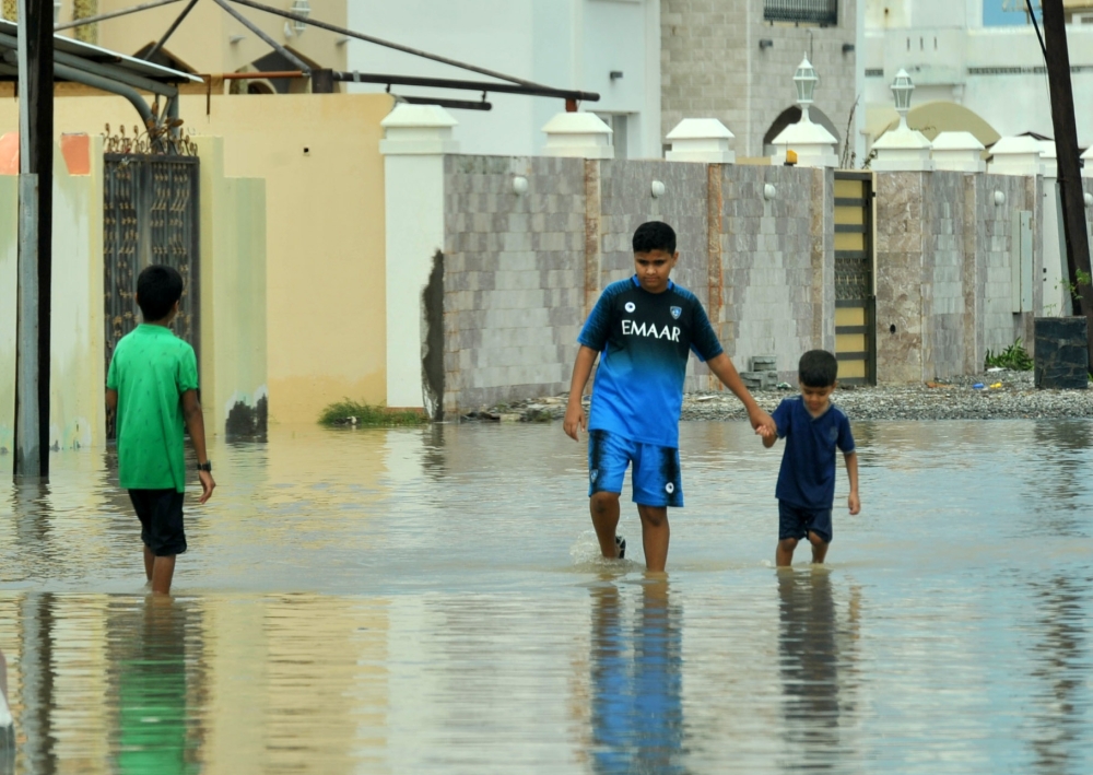 Locals walk on flooded streets caused by Cyclone Shaheen in Al Musanaa, Al Batina region, Oman, October 4, 2021. Oman News Agency/Handout via REUTERS