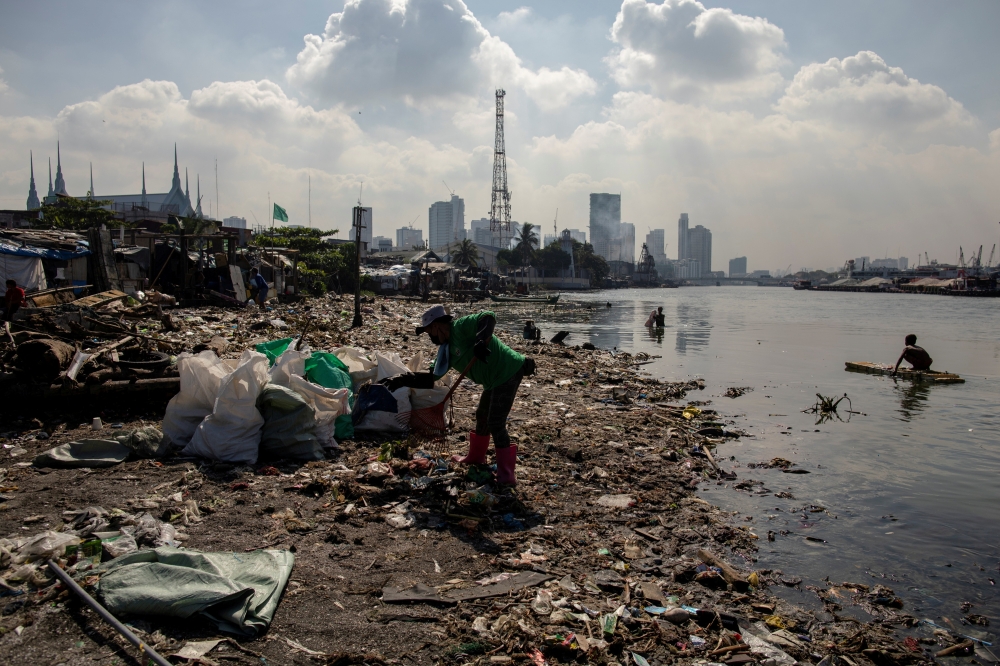 Angelita Imperio, a member of River Warriors, rakes through washed up trash from the heavily polluted Pasig River, at Baseco, Manila, Philippines, June 18, 2021. REUTERS/Eloisa Lopez/File Photo