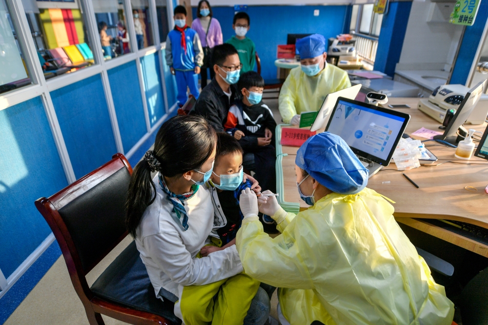 A medical worker administers a dose of a coronavirus disease (COVID-19) vaccine to a child in Huzhou, Zhejiang province, China October 26, 2021. China Daily via Reuters