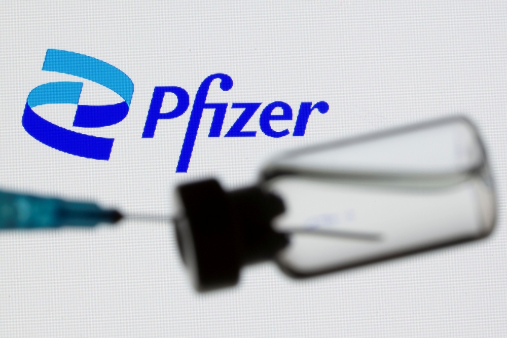 A syringe and vial are seen in front of a displayed Pfizer logo in this illustration taken June 24, 2021. REUTERS/Dado Ruvic/Illustration/File Photo