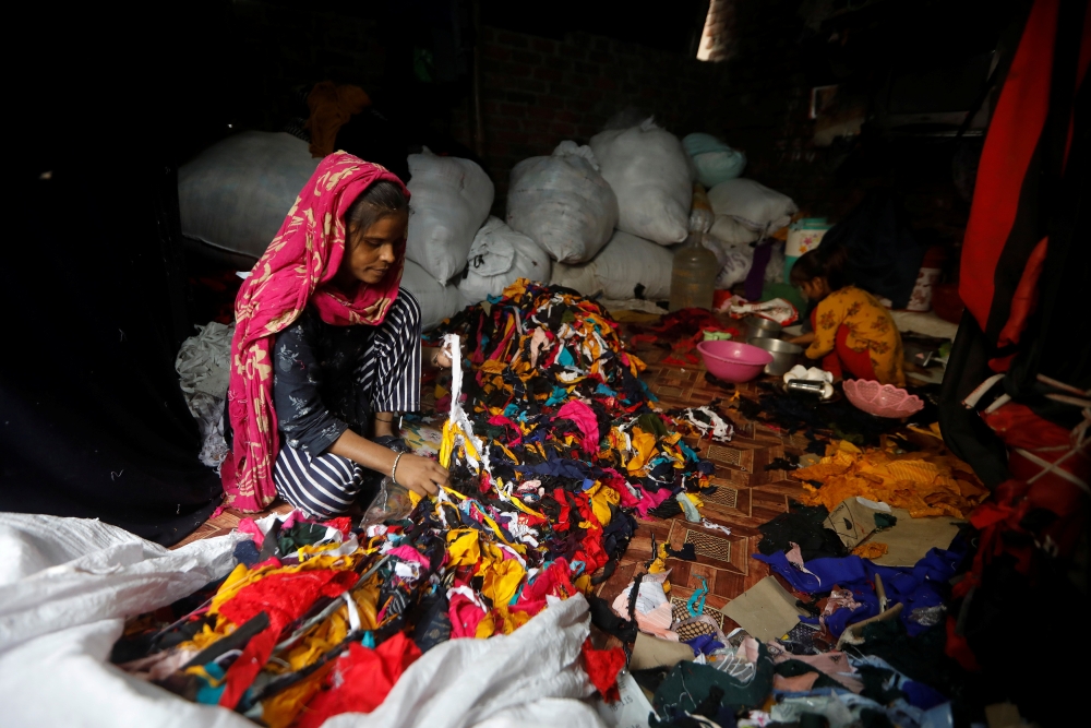 A woman sorts discarded fabric waste at a market in New Delhi, India, November 4, 2021. REUTERS/Adnan Abidi