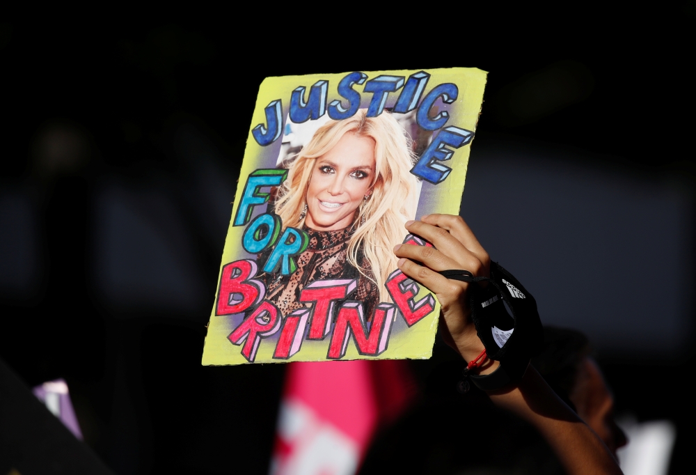 A supporter of singer Britney Spears holds up a picture of the pop star with the words 