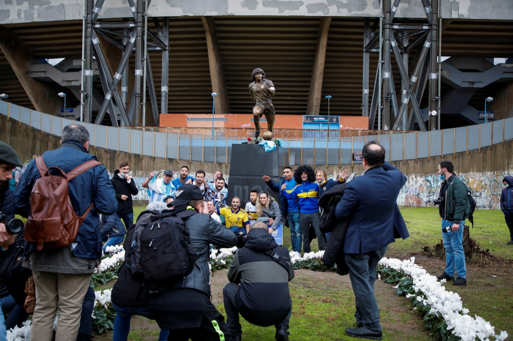 Fans of Argentinean soccer legend, Diego Armando Maradona, take photos during the unveiling ceremony of his statue in front of the stadium, on the first anniversary of his death, in Naples, Italy, November 25, 2021. REUTERS/Ciro De Luca
