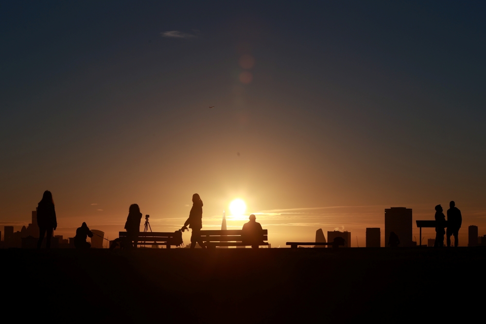 People watch the sun rise over the city's skyline from Primrose Hill in London, Britain, November 25, 2021. REUTERS/Hannah McKay