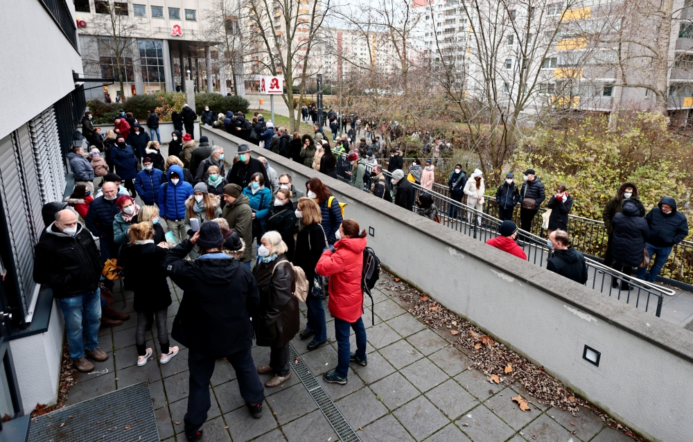 People wait outside of the practice of paediatrician Steffen Lueder during a weekend vaccination shift for over 400 people in Hohenschoenhausen, in Berlin, Germany, November 27, 2021. REUTERS/Hannibal Hanschke