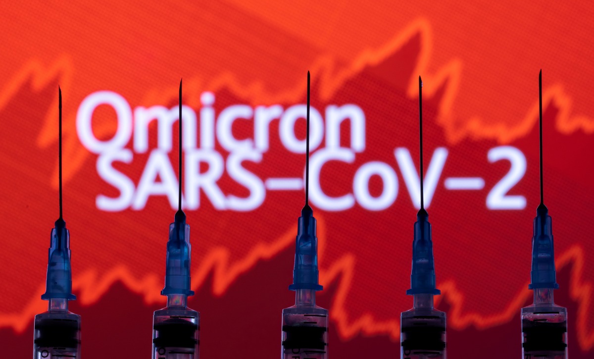 FILE PHOTO: Syringes with needles are seen in front of a displayed stock graph and words 