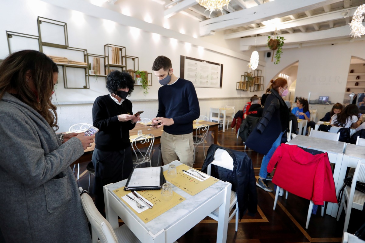 People have their coronavirus disease (COVID-19) health passes, known as Green Passes, checked at a restaurant, on the day before health passes become mandatory on public transport, in Rome, Italy December 5, 2021. REUTERS/Remo Casilli
