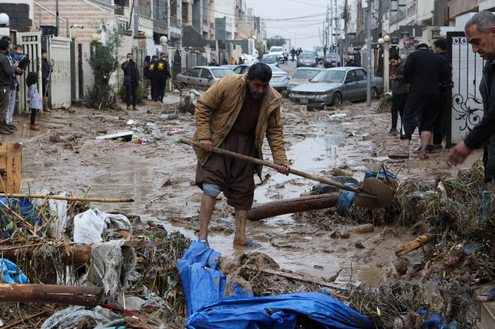 Residents clean a road full of mud after flash floods caused by torrential rains in Erbil, Iraq, December 17,2021. REUTERS/Azad Lashkari
