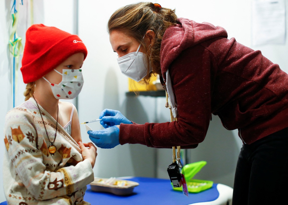 A nine-year-old girl receives a dose of the Pfizer-BioNTech vaccine for children against the coronavirus disease (COVID-19) during a vaccination event for children at the Lanxess Arena in Cologne, Germany, December 18, 2021. REUTERS/Thilo Schmuelgen
