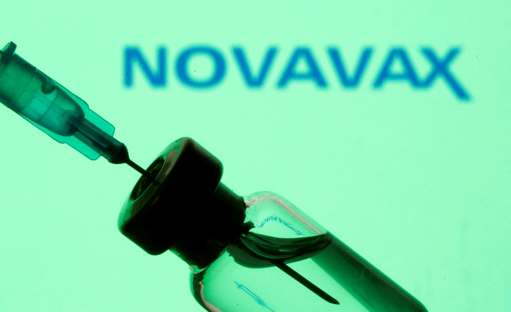 FILE PHOTO: A vial and sryinge are seen in front of a displayed Novavax logo in this illustration taken January 11, 2021. REUTERS/Dado Ruvic/Illustration