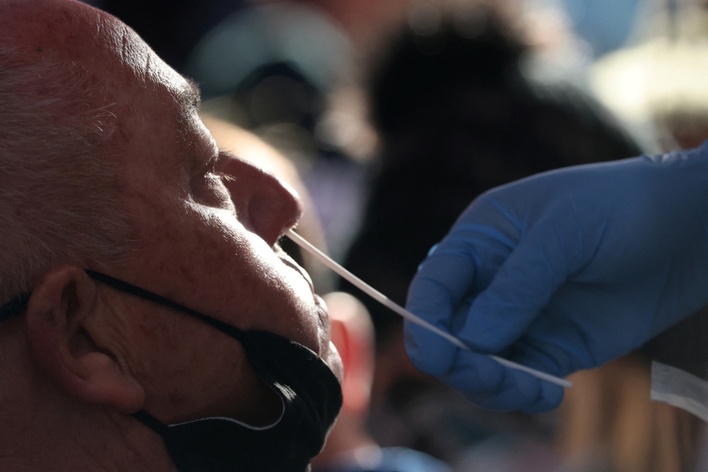 A person takes a COVID-19 test in Times Square as the Omicron coronavirus variant continues to spread in Manhattan, New York City, U.S., December 26, 2021. REUTERS/Andrew Kelly