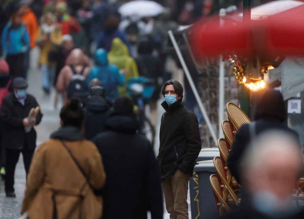 People wearing protective face masks are pictured on a rainy winter day in the Montorgueil street, amid the spread of the coronavirus disease (COVID-19) pandemic, in Paris, France, December 27, 2021. REUTERS/Christian Hartmann

