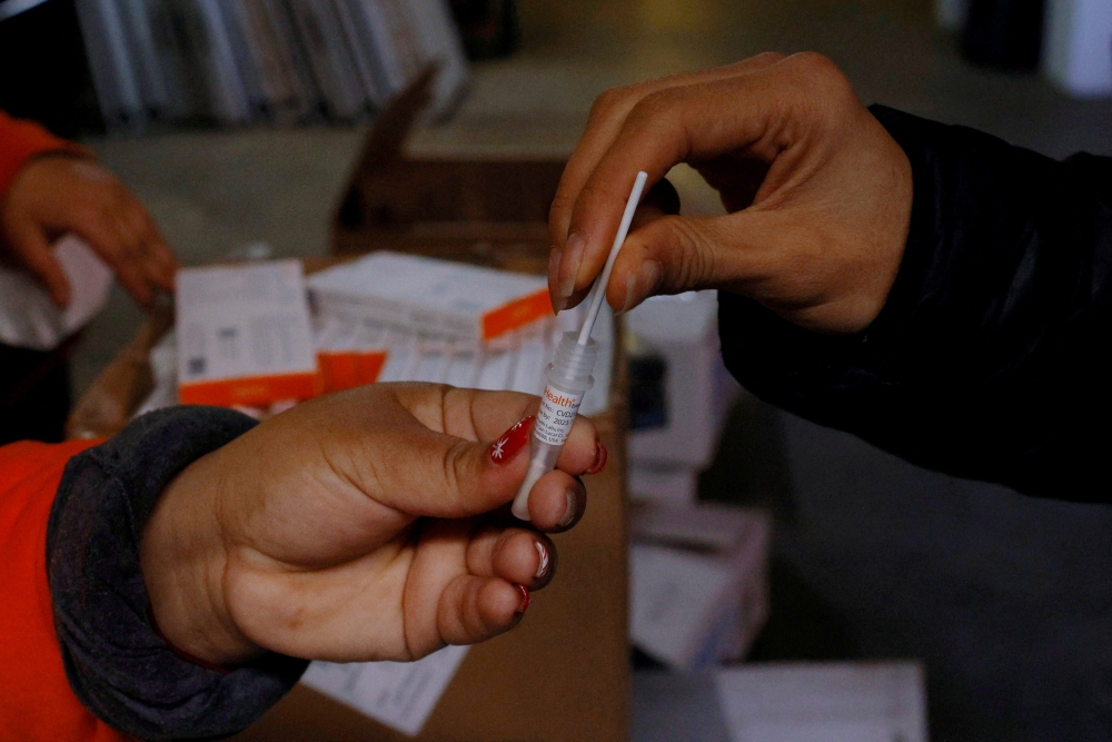 FILE PHOTO: A staff member uses a home coronavirus disease (COVID-19) test to check the heath of volunteers. REUTERS/Brian Snyder/File Photo
