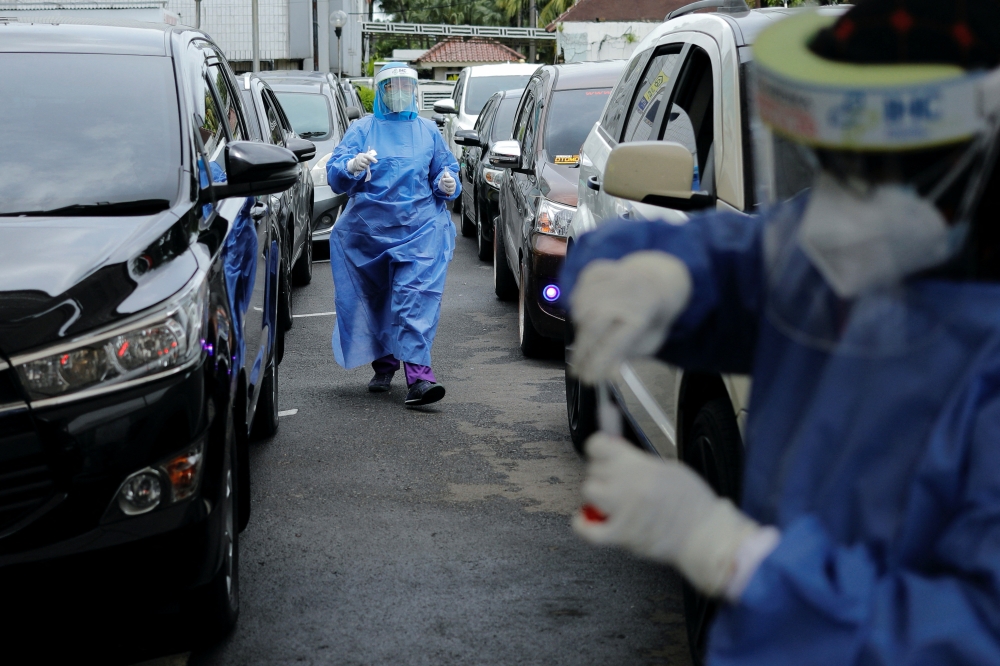 Medical workers prepare to take swab samples from people at a drive-thru coronavirus (COVID-19) test station, as the Omicron coronavirus variant spreads, in Jakarta, Indonesia, February 7, 2022. REUTERS/Willy Kurniawan