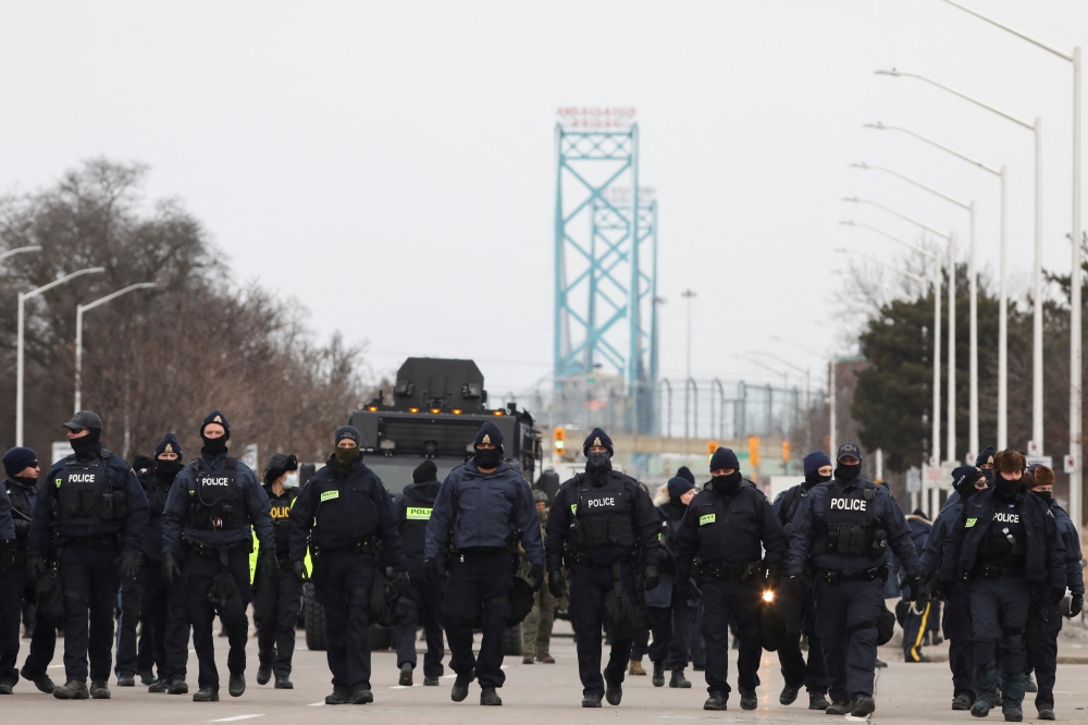 Police officers move along a road leading to the Ambassador Bridge, which connects Detroit and Windsor, after clearing demonstrators, during a protest against coronavirus disease (COVID-19) vaccine mandates, in Windsor, Ontario, Canada February 13, 2022. Reuters/Carlos Osorio