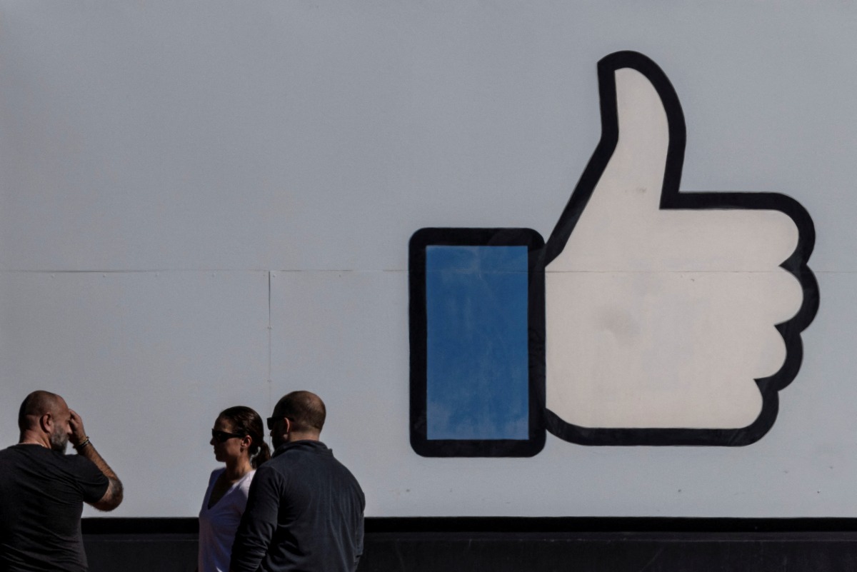 FILE PHOTO: People stand in front of the entrance sign to Facebook headquarters in Menlo Park, California, U.S. October 27, 2021. REUTERS/Carlos Barria/File Photo
