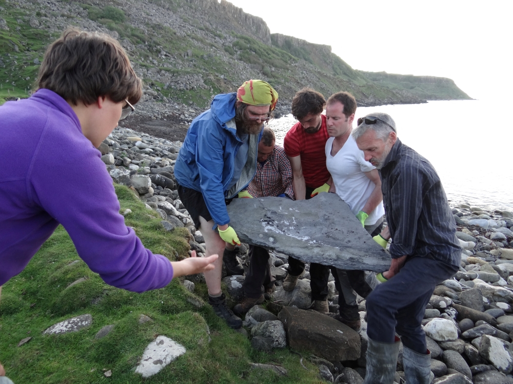 Researchers carry part of the fossil of a newly identified Jurassic Period flying reptile, or pterosaur, called 'Dearc sgiathanach', found on a rocky beach at Scotland's Isle of Skye, Britain in this handout image from May 2017. Shasta Marrero/Handout via Reuters