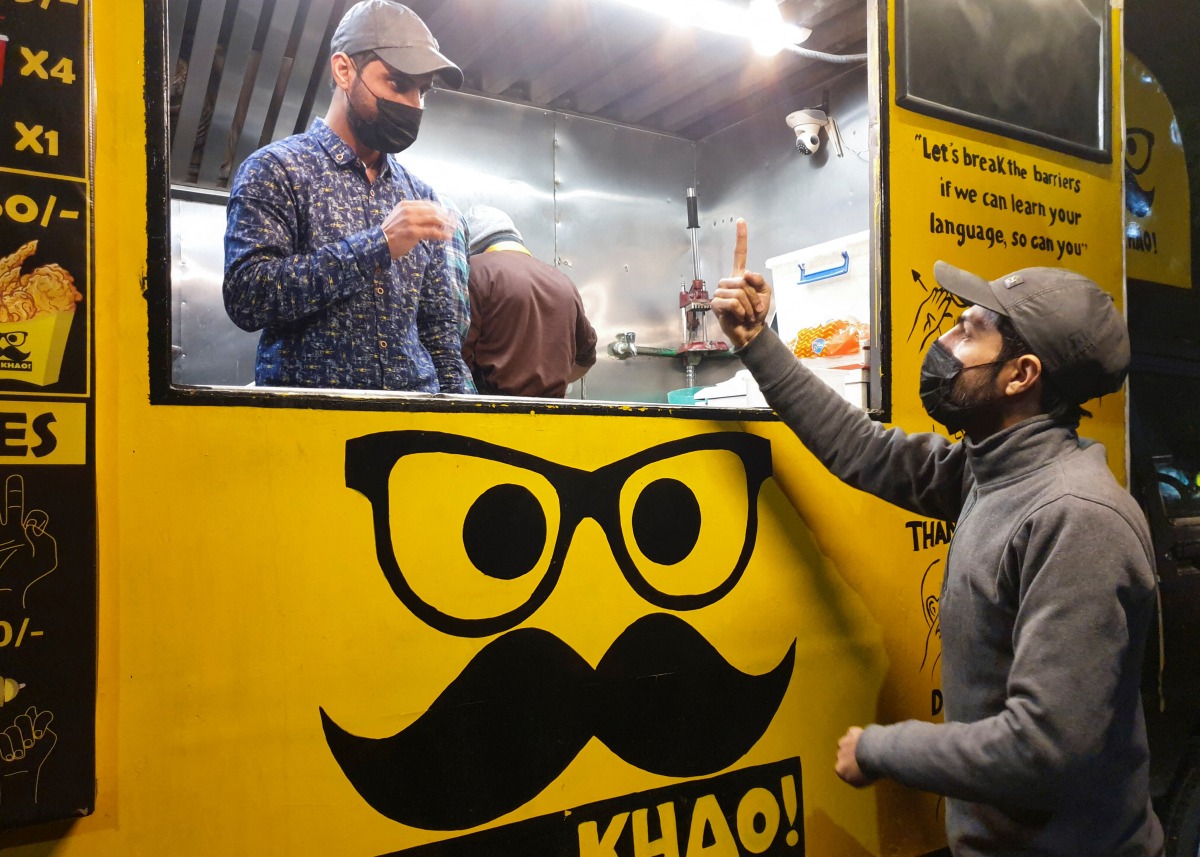 People communicate using sign language outside Pakistan's first mobile restaurant, staffed entirely by deaf workers, in Islamabad, Pakistan February 23, 2022. Picture taken February 23, 2022. REUTERS/Salahuddin NO RESALES. NO ARCHIVES.
