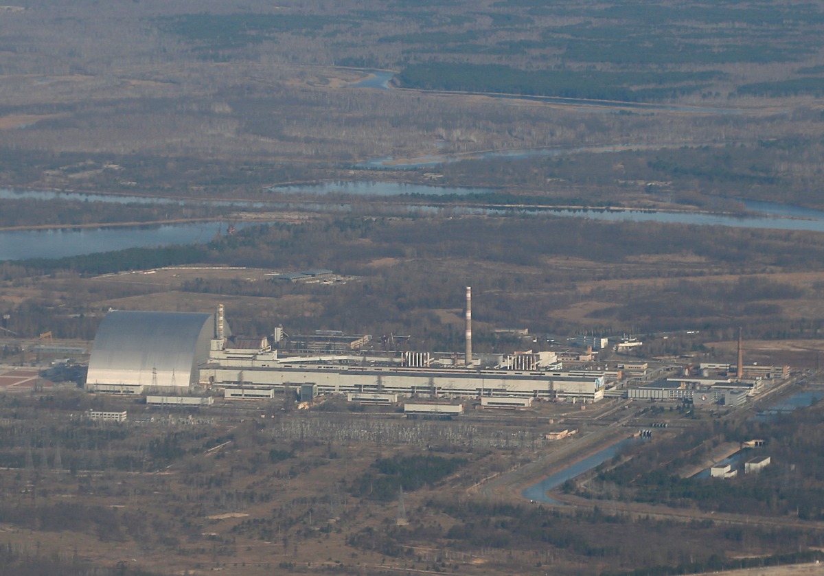 FILE PHOTO: An aerial view from a plane shows a New Safe Confinement (NSC) structure over the old sarcophagus covering the damaged fourth reactor at the Chernobyl Nuclear Power Plant during a tour to the Chernobyl exclusion zone, Ukraine April 3, 2021. REUTERS/Gleb Garanich/File Photo
