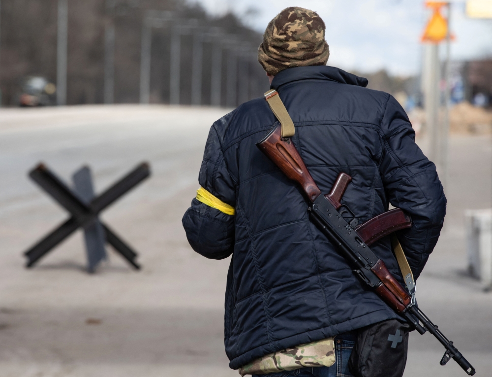 A member of the Territorial Defence Forces of Ukraine stands guard at a checkpoint on the outskirts of Kyiv, Ukraine February 27, 2022. REUTERS/Mikhail Palinchak