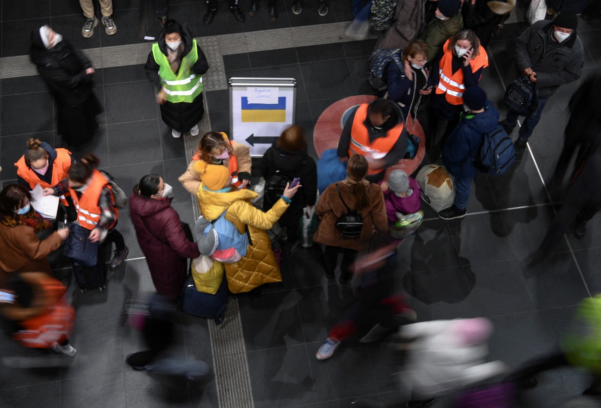 Volunteers in high-visibility clothing help refugees fleeing Russia's invasion of Ukraine who have arrived on a train from Poland at the central station in Berlin, Germany, March 6, 2022. Picture taken with a slow shutter speed. REUTERS/Annegret Hilse
