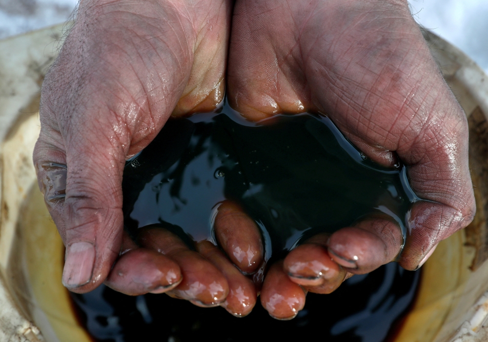 An employee holds a sample of crude oil at the Yarakta oilfield, owned by Irkutsk Oil Co, in the Irkutsk region, Russia on March 11, 2019. (Reuters/Vasily Fedosenko/File Photo)