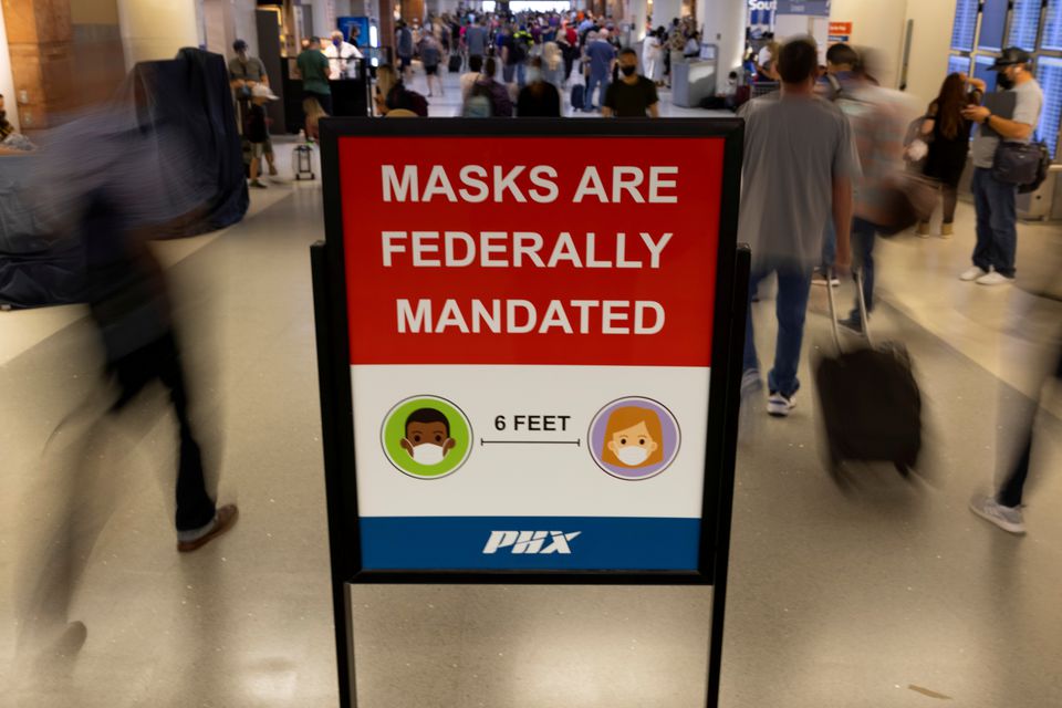 FILE PHOTO: Air travelers make their way past a sign mandating face masks for all during the outbreak of the coronavirus disease (COVID-19) at Phoenix international airport in Phoenix, Arizona, U.S. September 24, 2021. REUTERS/Mike Blake


