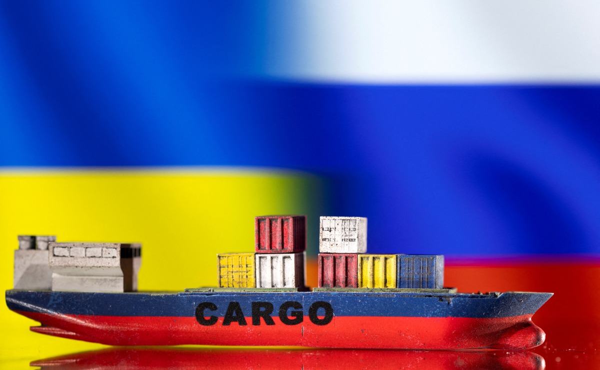 FILE PHOTO: A cargo ship boat model is pictured in front of Ukraine's and Russian's flags in this illustration taken March 3, 2022. REUTERS/Dado Ruvic/Illustration/File Photo
