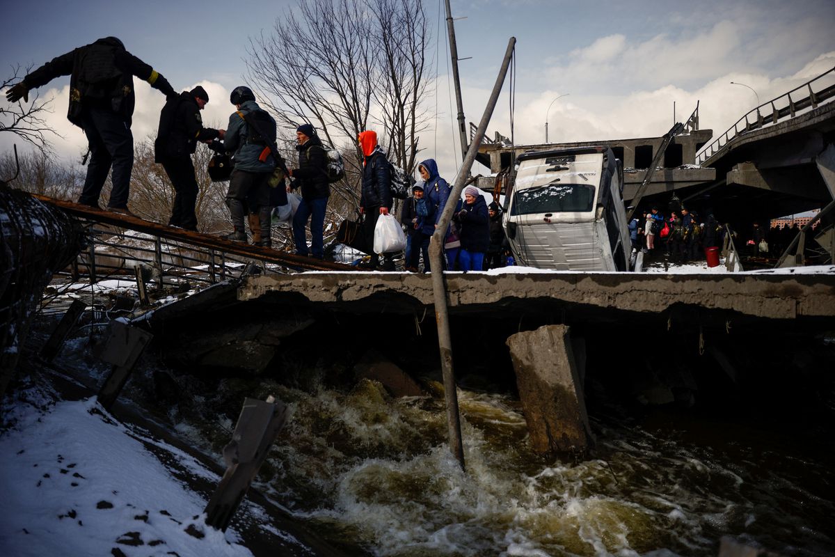 People file across a makeshift river crossing below a destroyed bridge as they flee from advancing Russian troops whose attack on Ukraine continues in the town of Irpin outside Kyiv, Ukraine, March 8, 2022. REUTERS/Thomas Peter

