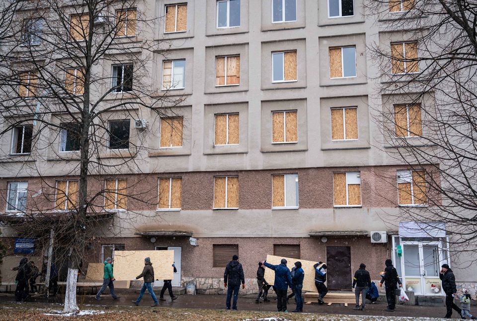 Men use sheets of plywood to cover windows of a hospital following shelling, as Russia's invasion of Ukraine continues, in Zhytomyr, Ukraine March 2, 2022. REUTERS/Viacheslav Ratynskyi/File Photo

