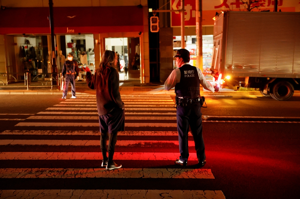 A police talks with a local resident on the street during an electric stoppage at the area after an earthquake in Tokyo, Japan March 17, 2022. REUTERS/Issei Kato
