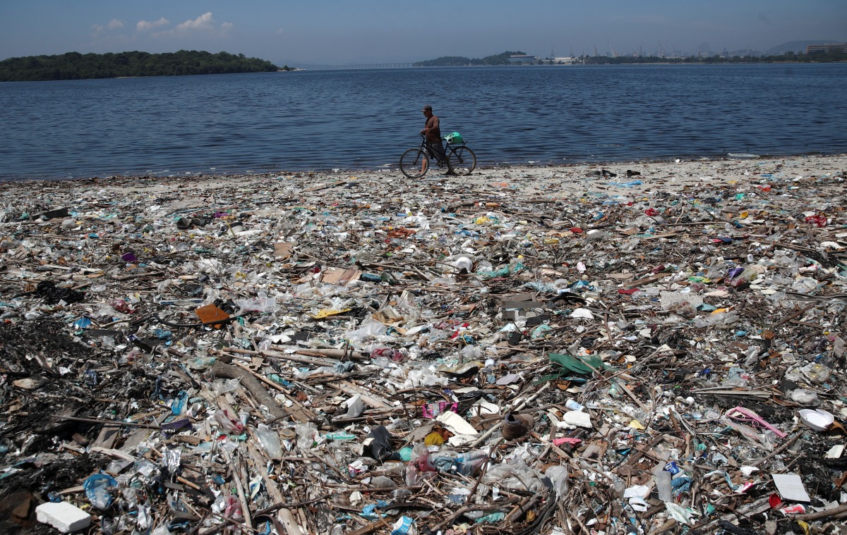 A man walks by garbage at a polluted beach on the banks of Guanabara Bay in Rio de Janeiro, Brazil March 16, 2022. REUTERS/Ricardo Moraes
