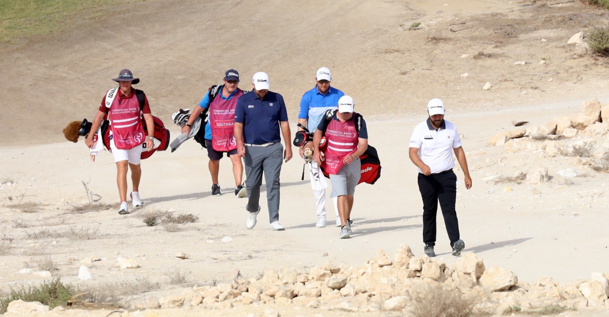 Players and their caddies walk at the Doha Golf Club during the opening round of Commercial Bank Qatar Masters, yesterday.
