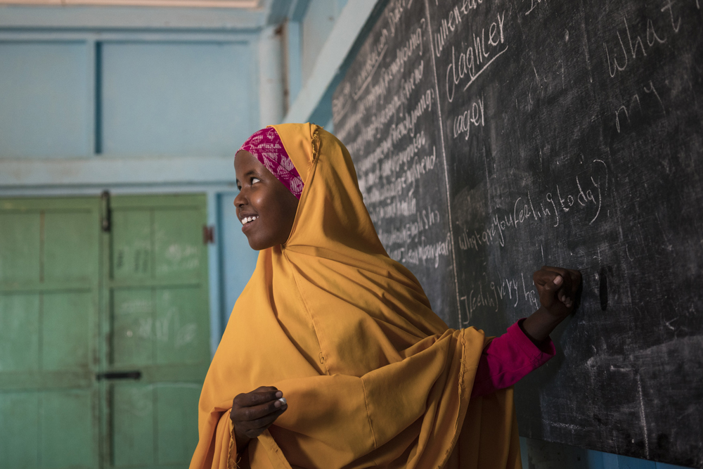 A young girl smiles as she looks back at her teacher for help answering a question during a class at her Unicef-supported primary school, Salaama, in Galkayo, Somalia, in this picture taken on April 12, 2017.