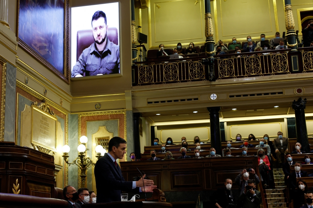 Spanish Prime Minister Pedro Sanchez speaks as Ukrainian President Volodymyr Zelenskiy appears on a screen as he addresses members of Spanish parliament via video link, amid Russia's invasion of Ukraine, in Madrid, Spain, April 5, 2022. REUTERS.