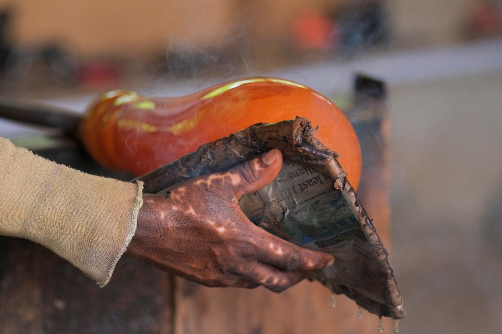 The scarred hand of Ghanaian glassblower Michael Tetteh, 44, is pictured as he shapes molten glass at his glassware manufacturing workshop in Krobo Odumase, Ghana March 15, 2022. Picture taken March 15, 2022. REUTERS/Francis Kokoroko