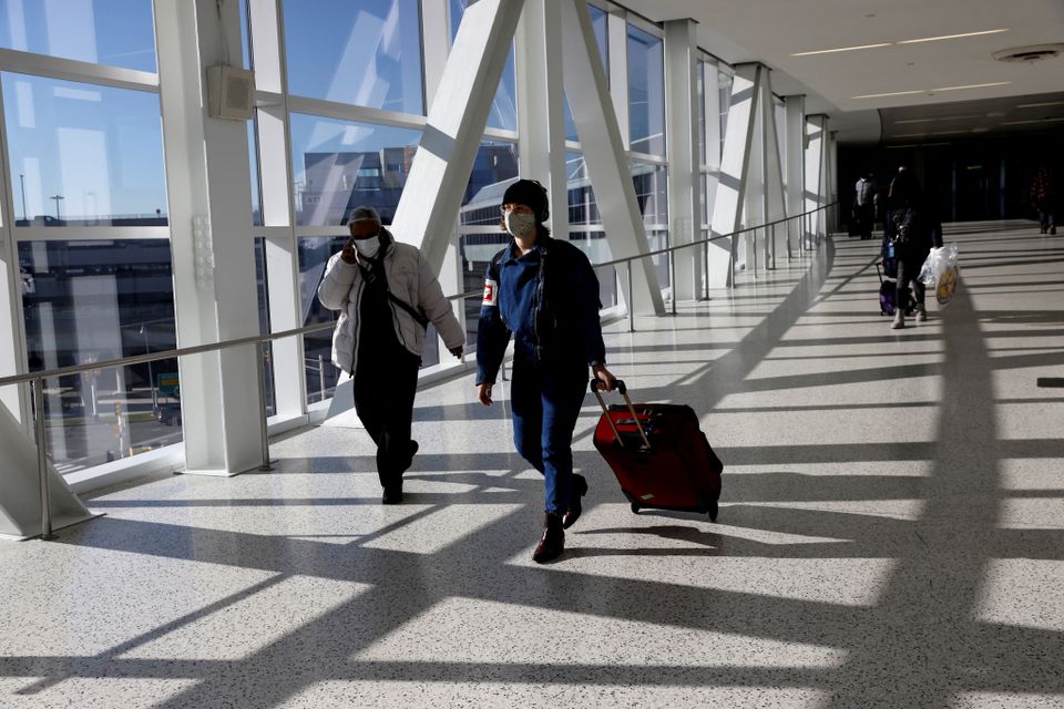 Air travellers wearing protective face masks, amid the coronavirus disease (COVID-19) pandemic, walk at JetBlue Terminal 5 at JFK International airport in New York, U.S., November 16, 2021. REUTERS/Shannon Stapleton


