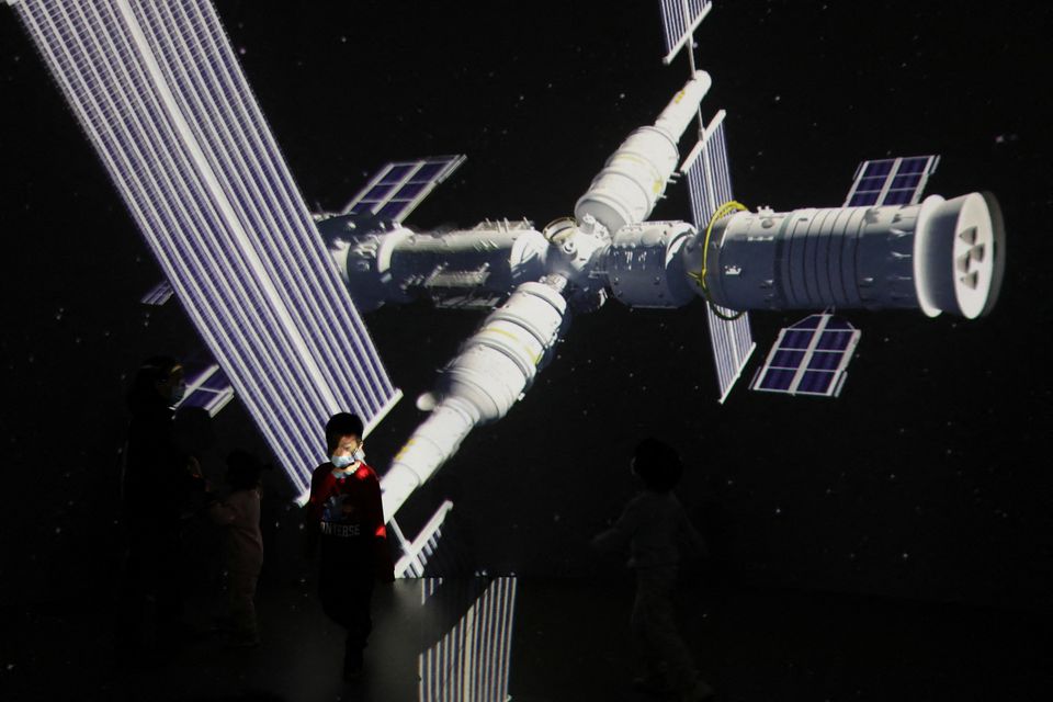 A child stands near a giant screen showing the image of the Tianhe space station on the country's Space Day at China Science and Technology Museum in Beijing, China April 24, 2021. Reuters/Tingshu Wang/File Photo

