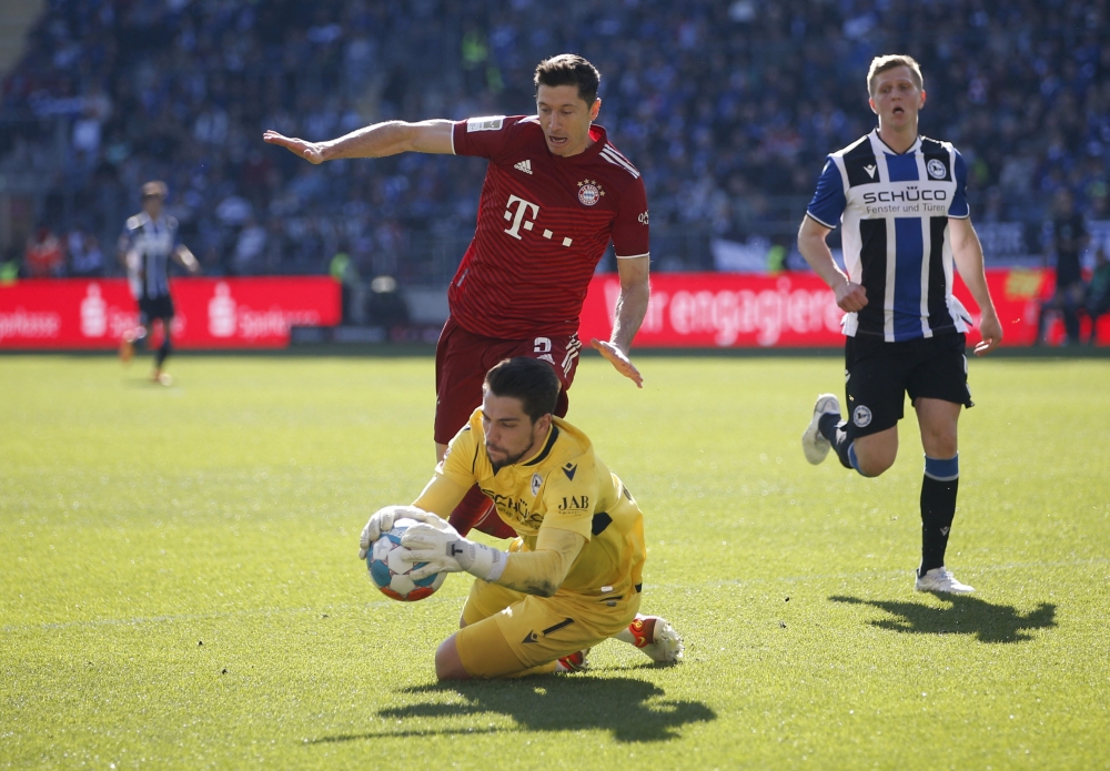 Bayern Munich's Robert Lewandowski in action with Arminia Bielefeld's Stefan Ortega REUTERS/Leon Kuegeler DFL REGULATIONS PROHIBIT ANY USE OF PHOTOGRAPHS AS IMAGE SEQUENCES AND/OR QUASI-VIDEO.
