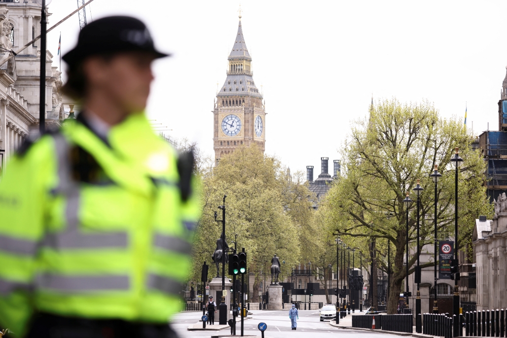 A forensic official and police officers work at a cordon on Whitehall in Westminster after the road was closed by police following an incident involving the arrest of a man near Downing Street, in London, Britain, April 18, 2022. REUTERS/Henry Nicholls