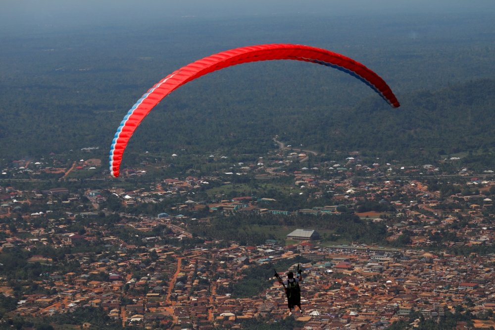 A paraglider flies with a passenger during the annual Easter paragliding festival in Kwahu-Atibie, Ghana April 15, 2022. Picture taken April 15, 2022. REUTERS/Francis Kokoroko