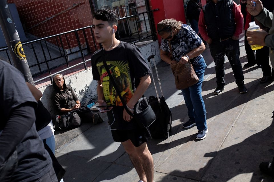 People wait in line to cross the San Ysidro Port of Entry of the Mexico-U.S. border, as the U.S. reopens air and land borders to coronavirus disease (COVID-19) vaccinated travellers for the first time since the COVID-19 restrictions were imposed in Tijuana, Mexico November 9, 2021. REUTERS/Toya Sarno Jordan

